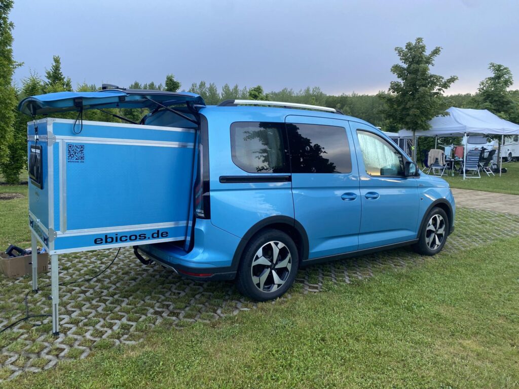 Ausgezogenes ebicos Modul im Heck eines blauen Ford Tourneo Connect auf einem Campingplatz